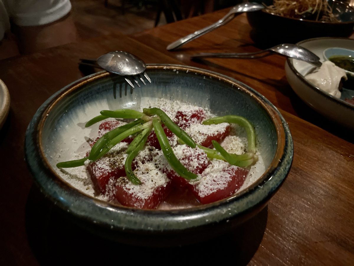 A bowl with watermelon covered in shaved, white feta and topped with a large piece of pigface succullent.