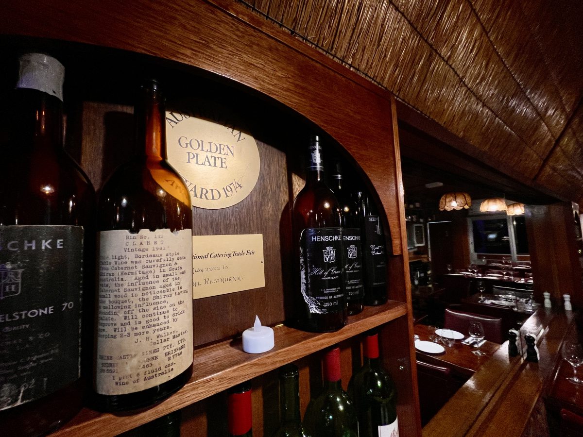 A shelf with a very old empty wine bottle. The printed label has tasting notes and details about the wine, like 1961 vintage, Claret.