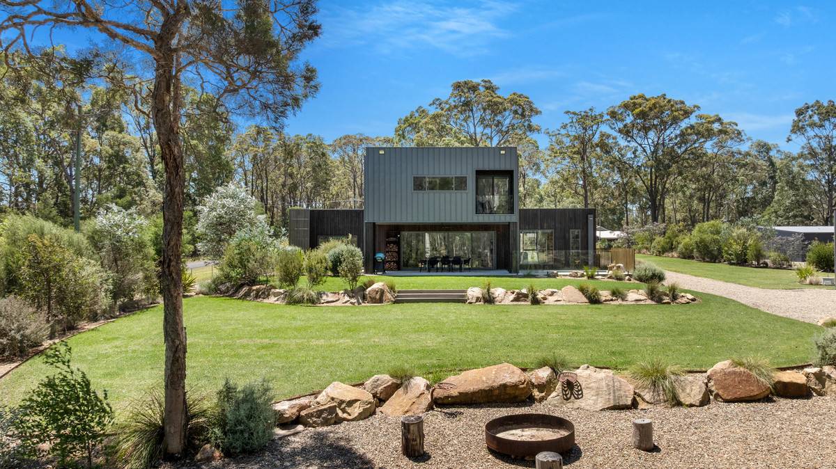 back of modern home with covered outdoor entertainment, lush lawns and firepit