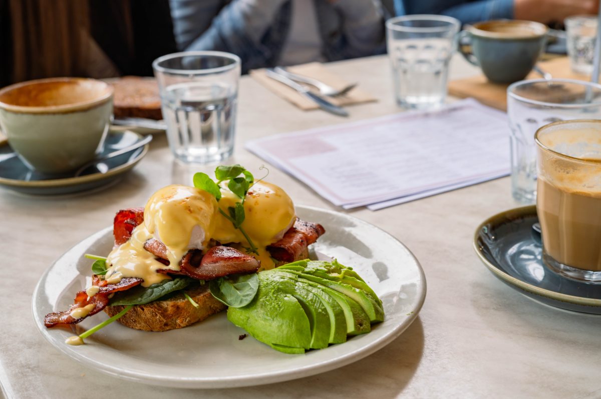a plate of cafe breakfast surrounded by cups and glasses