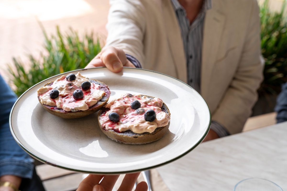 a hand holds out a plate of food