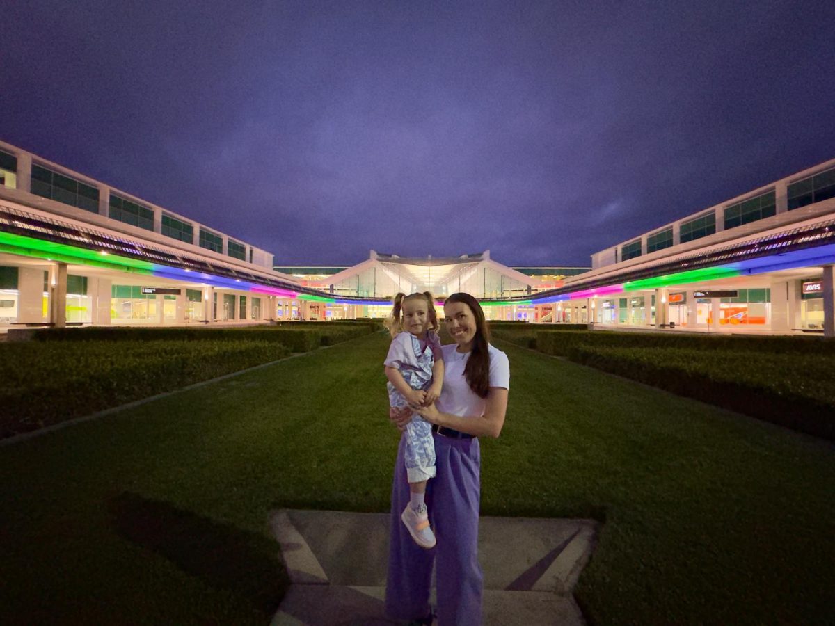 A woman holding her young child in front of an illuminated building