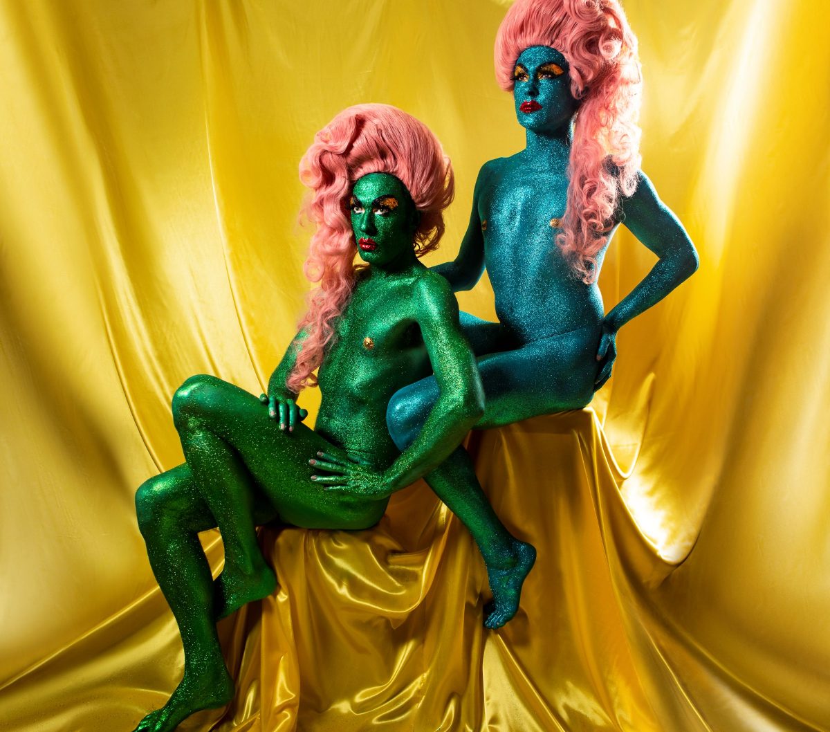 The Huxleys posing in costume surrounded by gold satin