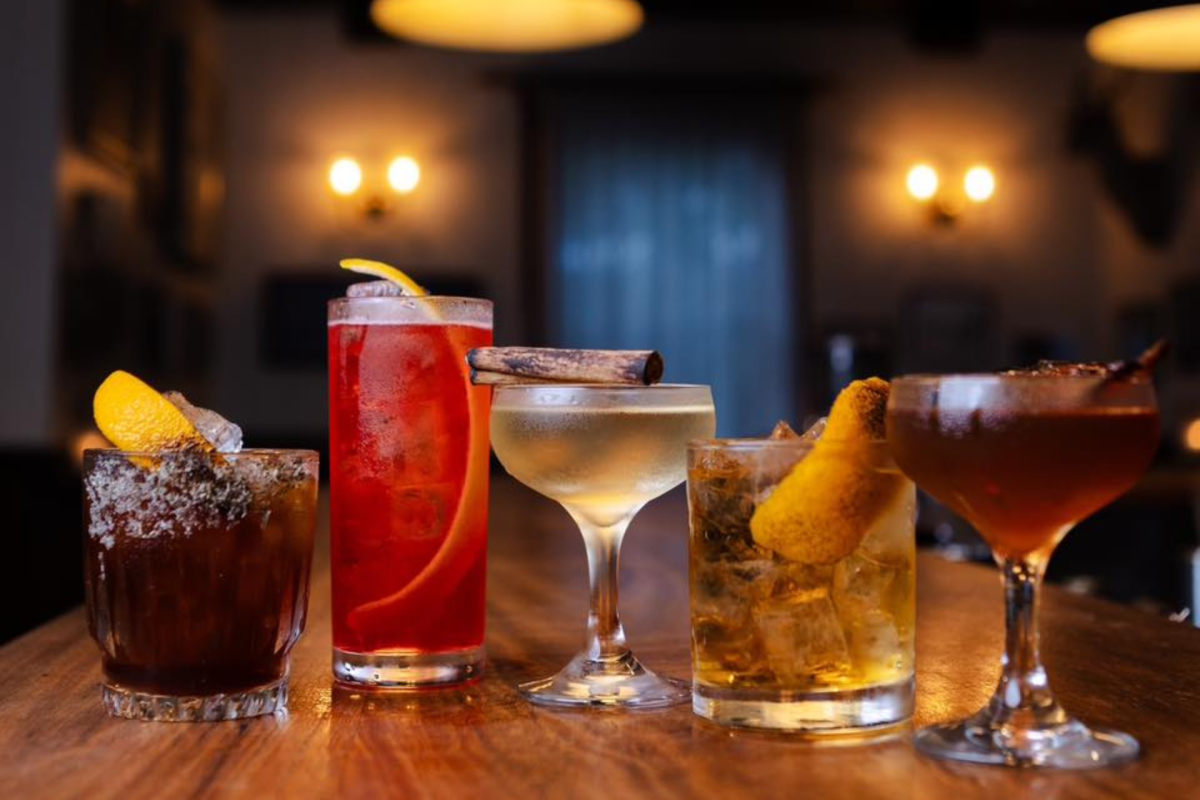A row of colourful drinks on a bar