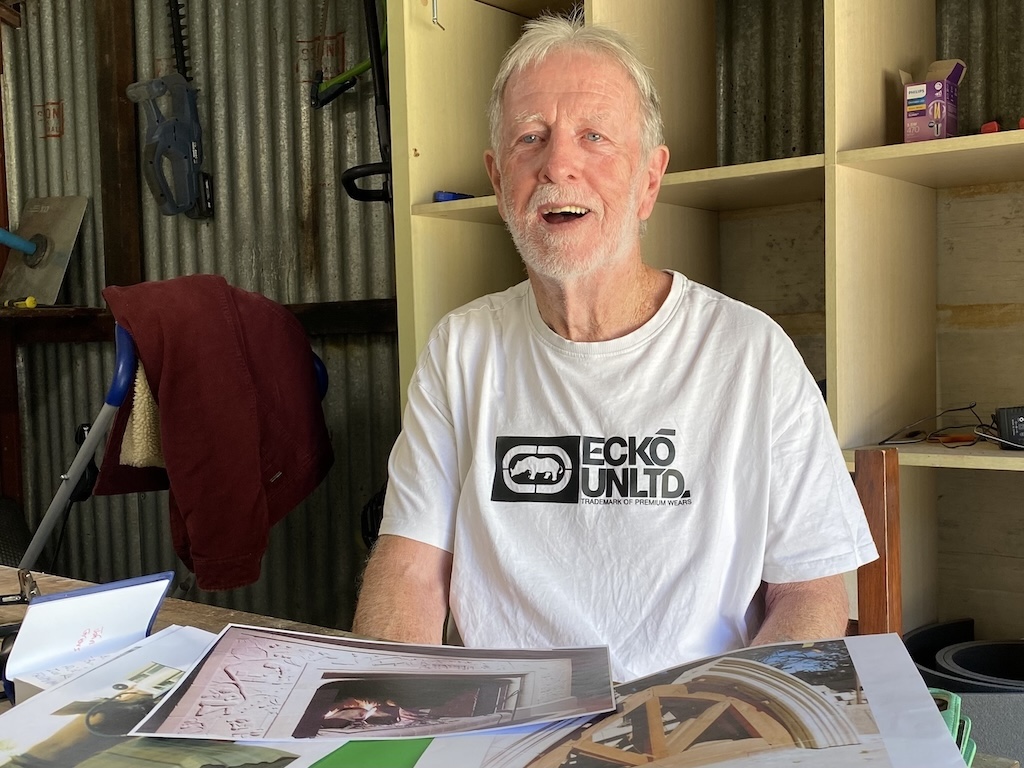 Michael Beville with photographs of past projects, including the stone frame of his fireplace in his Southern Highlands home, which he carved with symbols telling the story of his life.