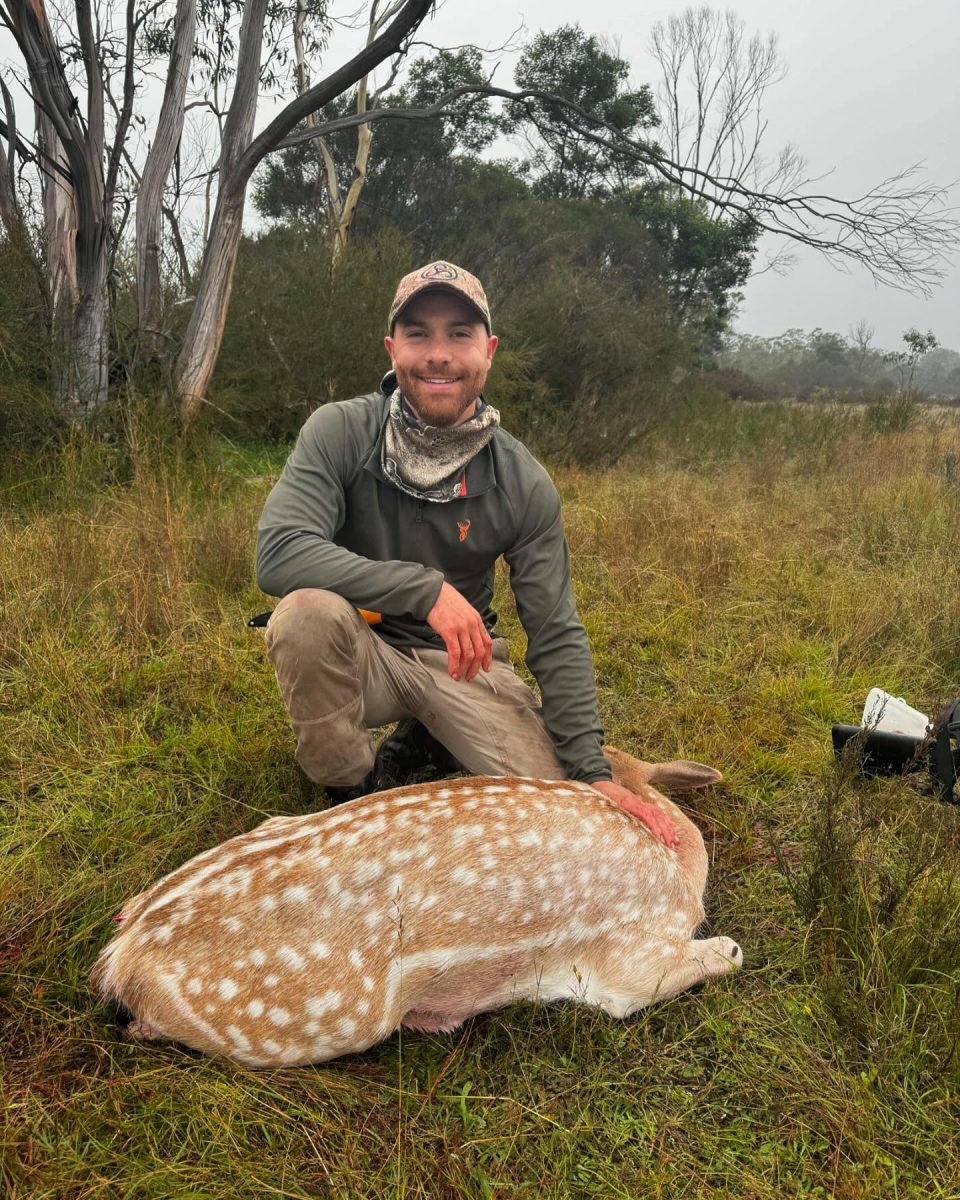 A man kneeling over a dead deer
