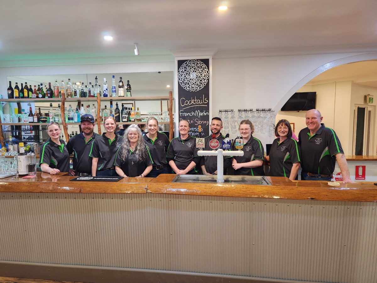 A group of people in their work shirts standing behind a bar