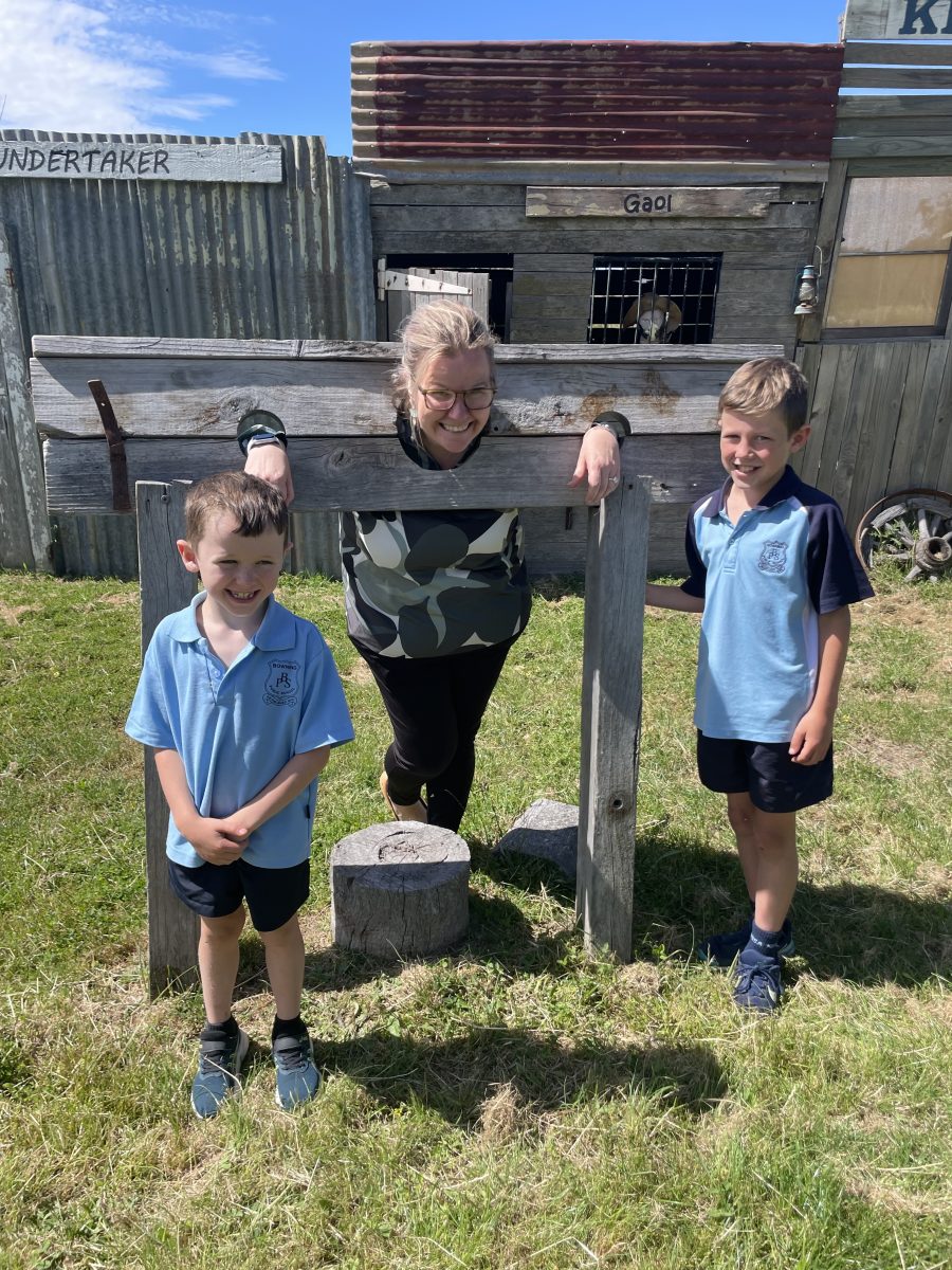 Woman with her head in stocks with two children.