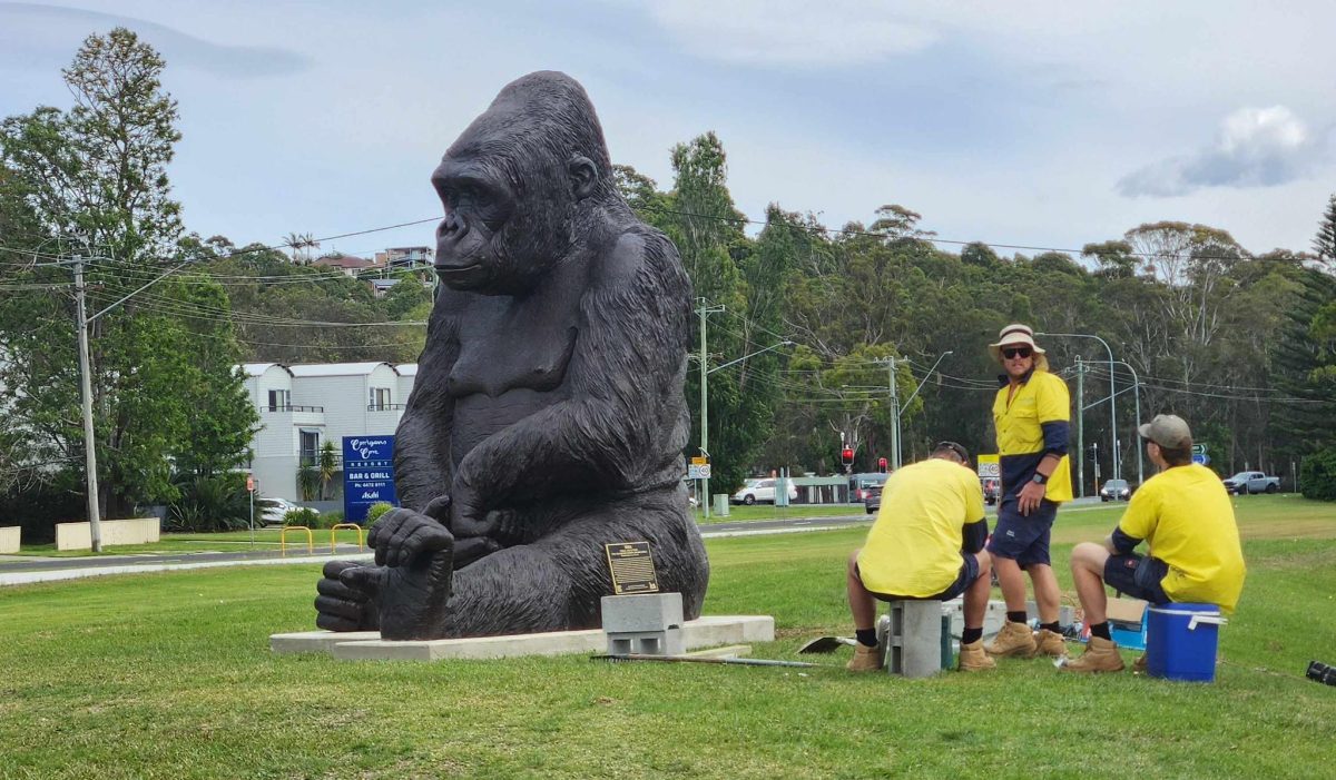 Three men in high-vis standing next to the 'Mina' statue