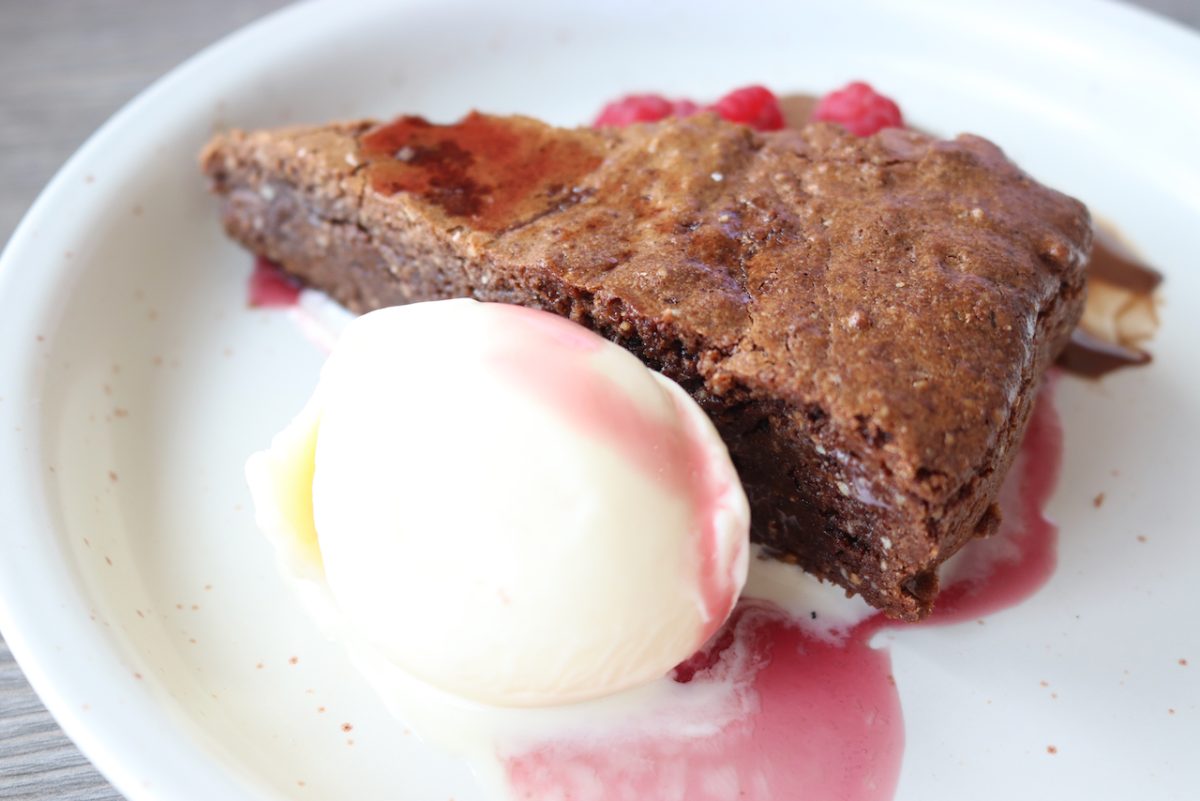 A slice of chocolate cake with a scoop of vanilla icecream.