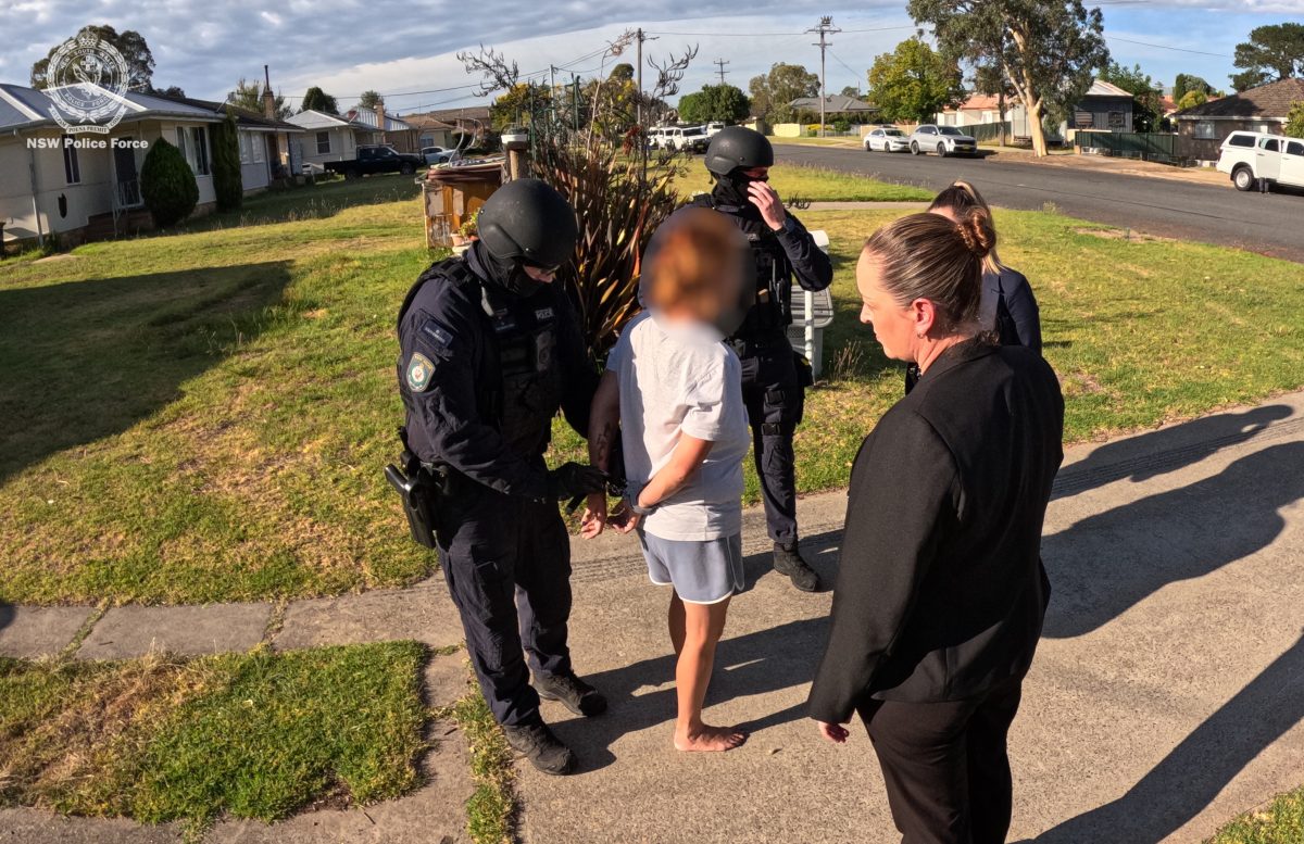 A police officer putting handcuffs on someone, whose face is blurred