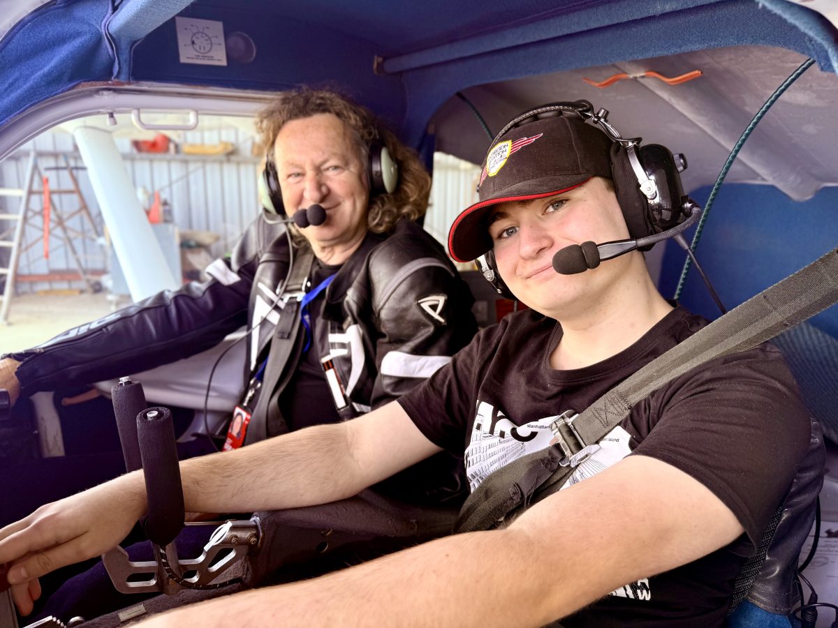A man and a teenage boy in the cockpit of a small plane
